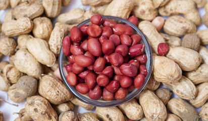 Red peanut or groundnut isolated white background. Peeled peanut on peanut group on glass bowl. Organic fresh raw food it called Arachis hypogaea on Latin name.