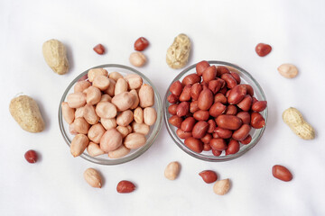 Red and pink peanut or groundnut isolated white background. Peeled peanut on peanut group on glass bowl. Organic fresh raw food it called Arachis hypogaea on Latin name.