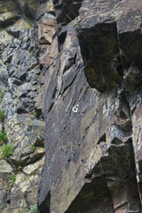 Dramatic view of a rocky cliff face with climbing gear attached.