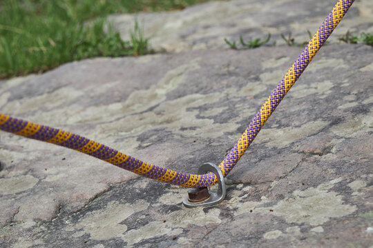 Climbing rope attached to a rock face via a secure bolt, ready for the ascent.