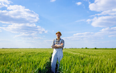 Portrait of adult male farmer standing in green wheat field looking at camera.