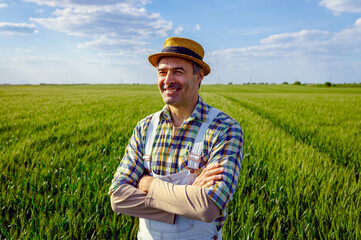 Portrait of adult male farmer standing in green wheat field.