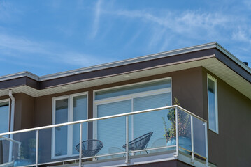 Top of grey stucco luxury house with shingle roof, green trees and nice windows in Spring in...