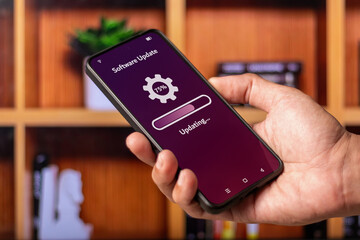 Hand holding a smartphone with process of updating software system or application on screen