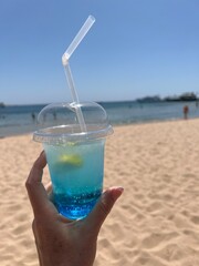 Cold Blue Lagoon cocktail with a blurred beach and sea in the background