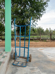 Blue Cart Against House Pillar for Goods Transport.