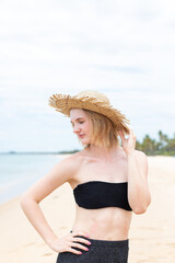 Portrait of stylish woman with straw hat standing at beach. Young woman on vacation enjoy sea...