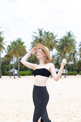 Portrait of stylish woman with straw hat standing at beach. Young woman on vacation enjoy sea...