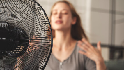 Woman cooling down by ventilator at home