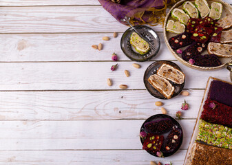 Sliced ​​Turkish delight assortment with cream filling, pistachio, almond, hazelnut, figs and cranberry laid out on plates on a white table. Local name: fistikli fitil lokum. Copy space