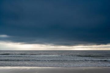 Fototapeta premium Dramatic dark sky stretches over a vast ocean with gentle waves, hinting at an impending storm or just after rain