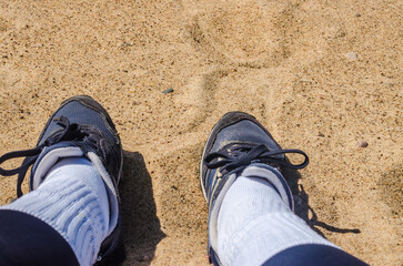 Close-up of sneakers on sandy beach with visible footprints. High quality photo