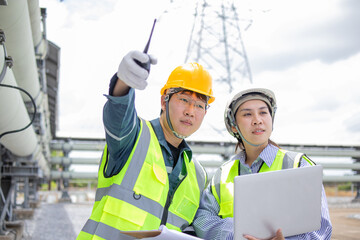 Two engineers working at power station are inspecting equipment with focus and determination while...