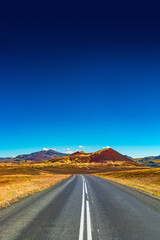 Cover page with a paved road, Ring road, through rough and colorful Icelandic landscape, Iceland, summer, suny blue sky, copy space