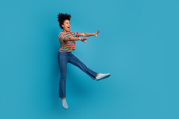 Youthful woman in vibrant striped t-shirt enjoying a casual moment on turquoise background,...