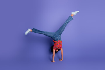 Young female performing an energetic handstand against a vibrant purple background, showcasing a...