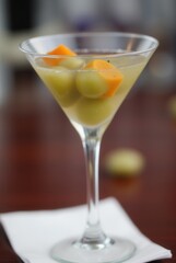Zesty Cocktail: A close-up shot of an elegant martini glass, featuring a refreshing cocktail with vibrant olive and cucumber, evoking sophistication and refined taste.