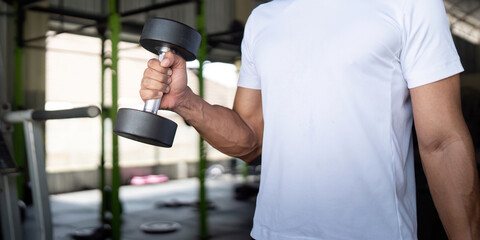 Focused Exercise. Young man lifting a dumbbell in gym for strength and fitness.