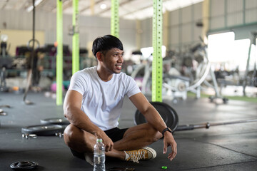 Fitness and Motivation. Young man smiling while resting in gym after workout.