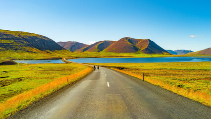 Panorama with a paved road, Ring road, through rough and colorful Icelandic landscape, Iceland, summer, suny blue sky