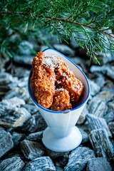 Spicy fried chicken, herb-coated, served in a quirky dish on rocky ground
