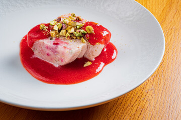 The plate showcases a luscious panna cotta topped with berry sauce and crunchy pistachios
