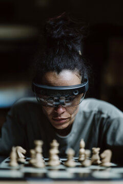 Woman wearing augmented reality glasses focusing on a chessboard, symbolizing human-AI interaction, concentration, strategy and modern immersive technology