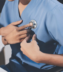 A physician uses a stethoscope to examine a patient's heart during a clinic appointment.