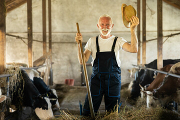 The farmer lifts his hat in celebration, capturing the joy of rural life and connection to agriculture amidst his cows.