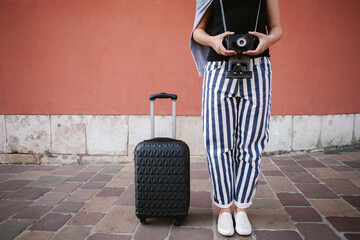 Young photographer traveling with suitcase and vintage camera