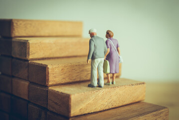 Old senior couple walking on high staircase. Aging society problem and prepare for retirement such as financial planning, healthcare costs, mental health, elder care burdens, social isolation concept.