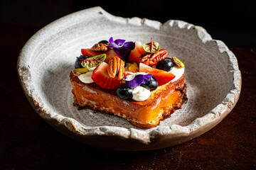 A stunning dessert adorned with fresh fruits, edible flowers, and nuts beautifully plated