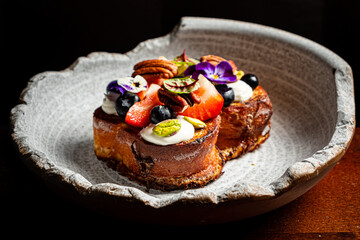 Exquisite dessert topped with vibrant berries and delicate flowers, served in a handcrafted dish