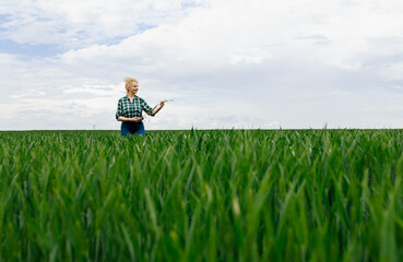 Portrait of adult female farmer standing in green wheat field.