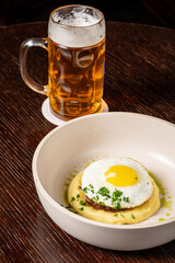 A plate of creamy mashed potatoes topped with a golden egg and chilled beer, beautifully served