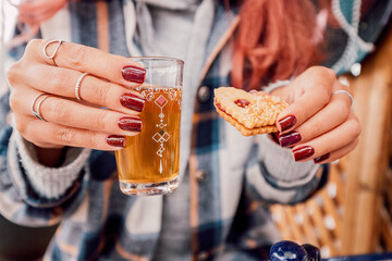 Woman holding a decorated glass of moroccan mint tea and a biscuit during her breakfast