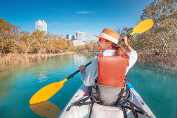 Woman paddling in kayak exploring mangrove park in Abu Dhabi, United Arab Emirates