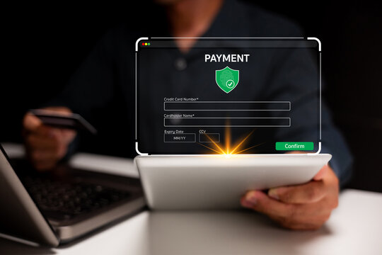 A person completes a secure online payment on a tablet, entering credit card details with a laptop in the background.
