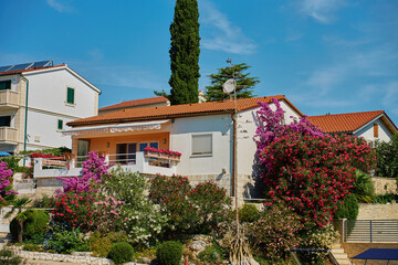 White Mediterranean house with large balcony and blooming garden. White villa with flowers near Adriatic coast. Coastal architecture in Croatia
