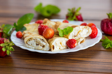 Pancakes with cottage cheese and strawberries on a wooden table
