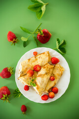 Homemade pancakes with cottage cheese filling and berries on a green background