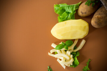 Potatoes in a sack and sliced into strips on a brown background