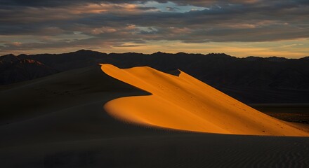 Fototapeta premium Sunlit Sand Dunes Under Dramatic Evening Sky