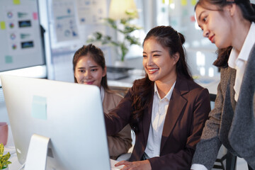 Obraz premium Group of young Asian businesswomen working and using desktop computer together discussing over new business project in modern office