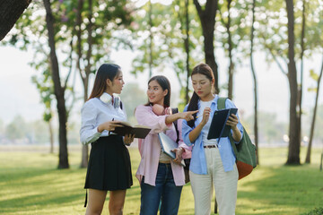 Obraz premium Three young women university students collaborating on a project outdoors, engaging in discussion while utilizing a laptop and tablet