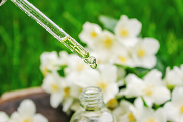 Jasmine essential oil in a glass bottle and jasmine flowers. Oils.