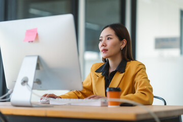 Focused businesswoman working diligently at her computer in a modern office, immersing herself in...