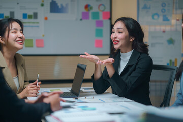 Asian businesswomen engaging in idea sharing and discussion during a meeting in a sleek, modern office environment