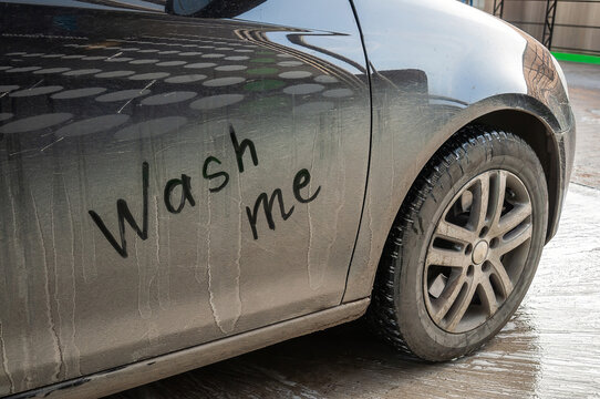 A close-up of a dirty car with a humorous request to be washed, Wash me.