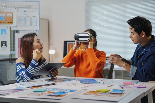 Uiux designers collaborating in the office, testing virtual reality headsets while developing a new mobile app prototype for enhanced user experience